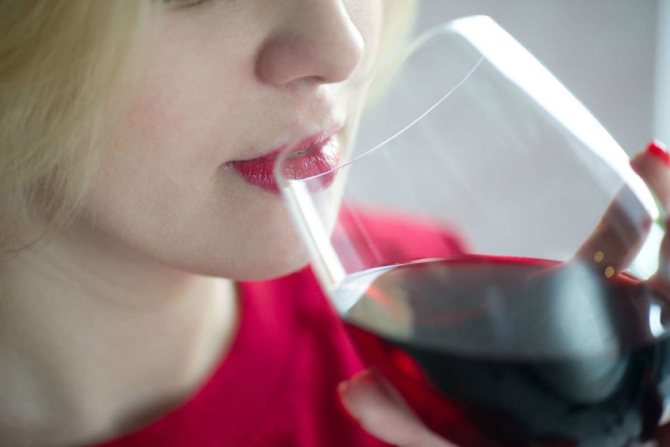 Девушка пьет красное вино из бокала