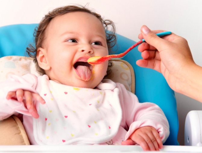 A child opens his mouth in front of a spoon with puree