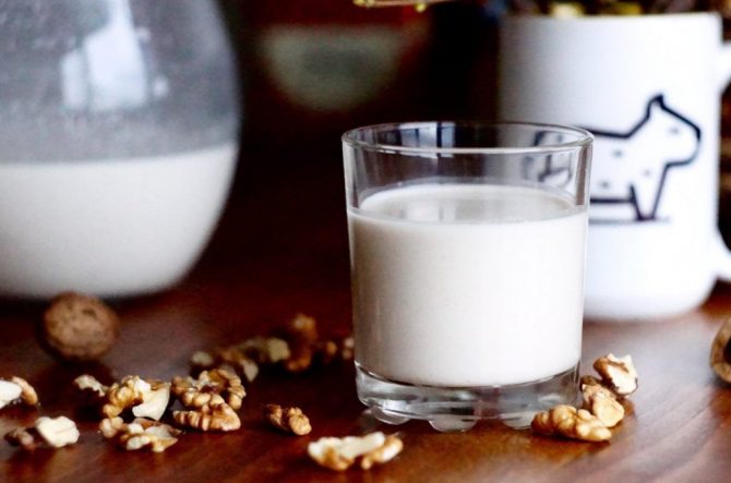 Glass of walnut milk and walnuts on the table