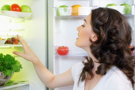 woman near an open refrigerator